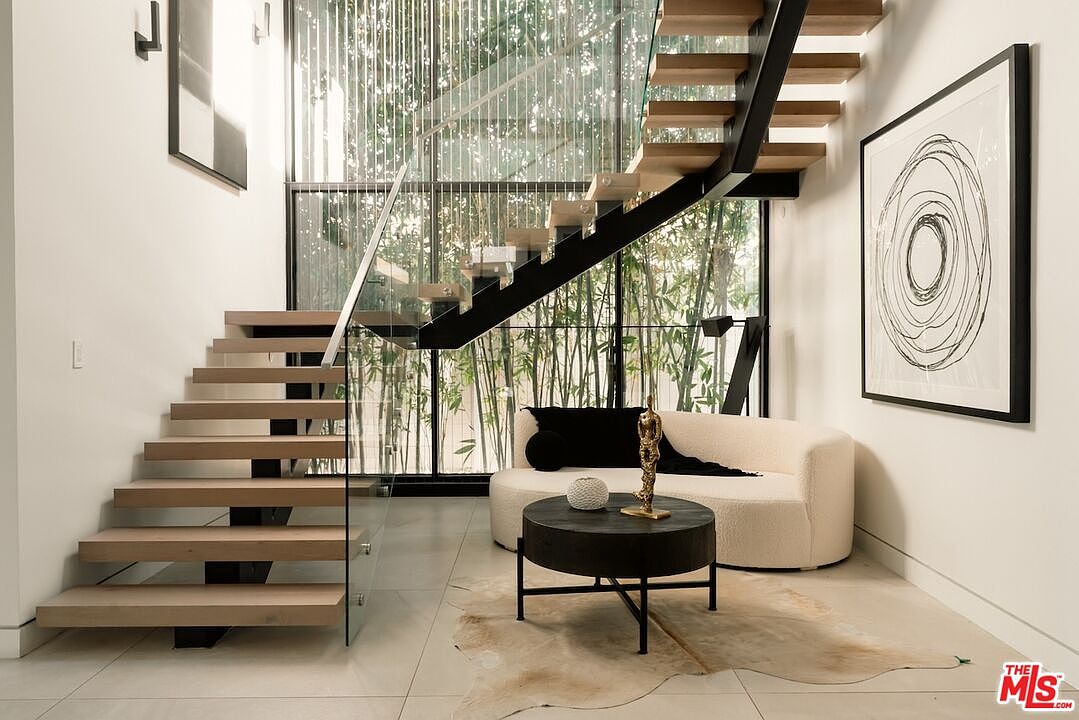 Floating staircase in white oak with glass guardrail, set against a wall of bamboo.