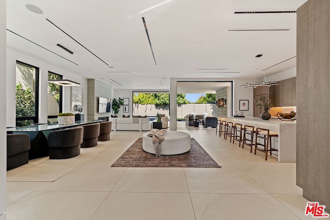 Open-plan great room with dining, kitchen, and retractable glass to the courtyard.
