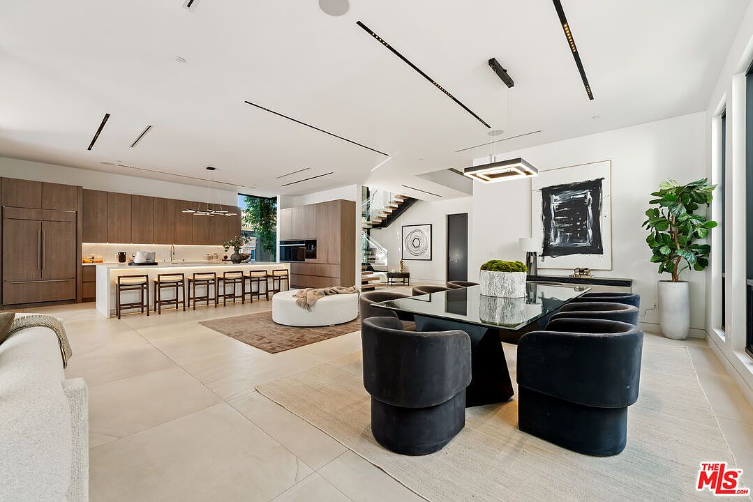 Open dining and living area with floor-to-ceiling windows and designer lighting.