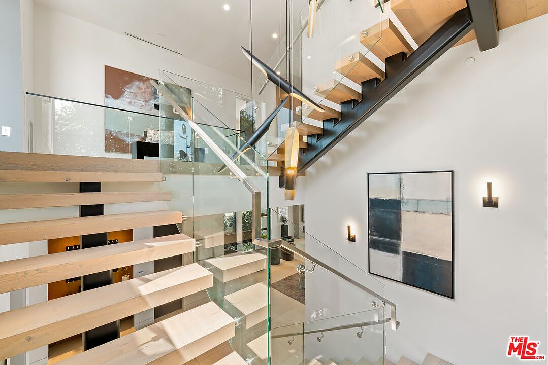 Floating oak staircase, viewed from below, with sculptural pendant light.